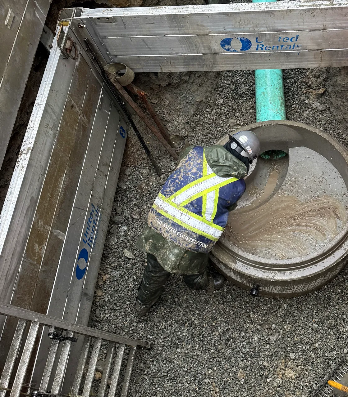 NSC crew member setting a manhole base inside a shoring box