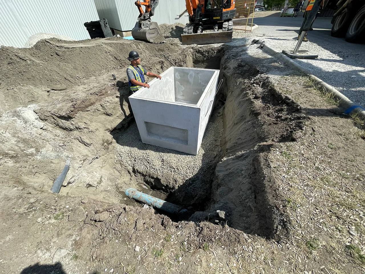 NSC crew setting a precast valve chamber with an excavator at Brighouse Elementary