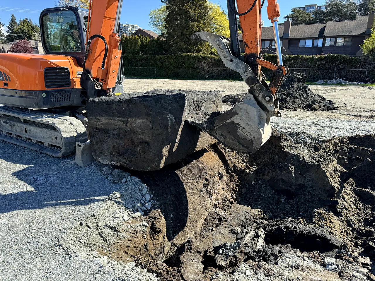 Excavator removing an old concrete slab during site prep