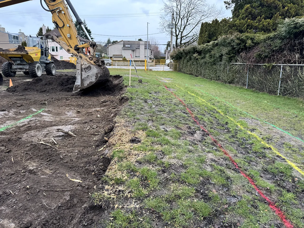 Excavator and site dumper stripping topsoil along the field edge