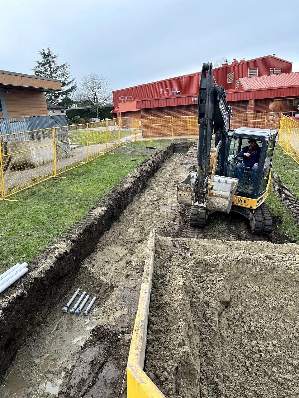 Excavator digging the electrical duct trench beside the school
