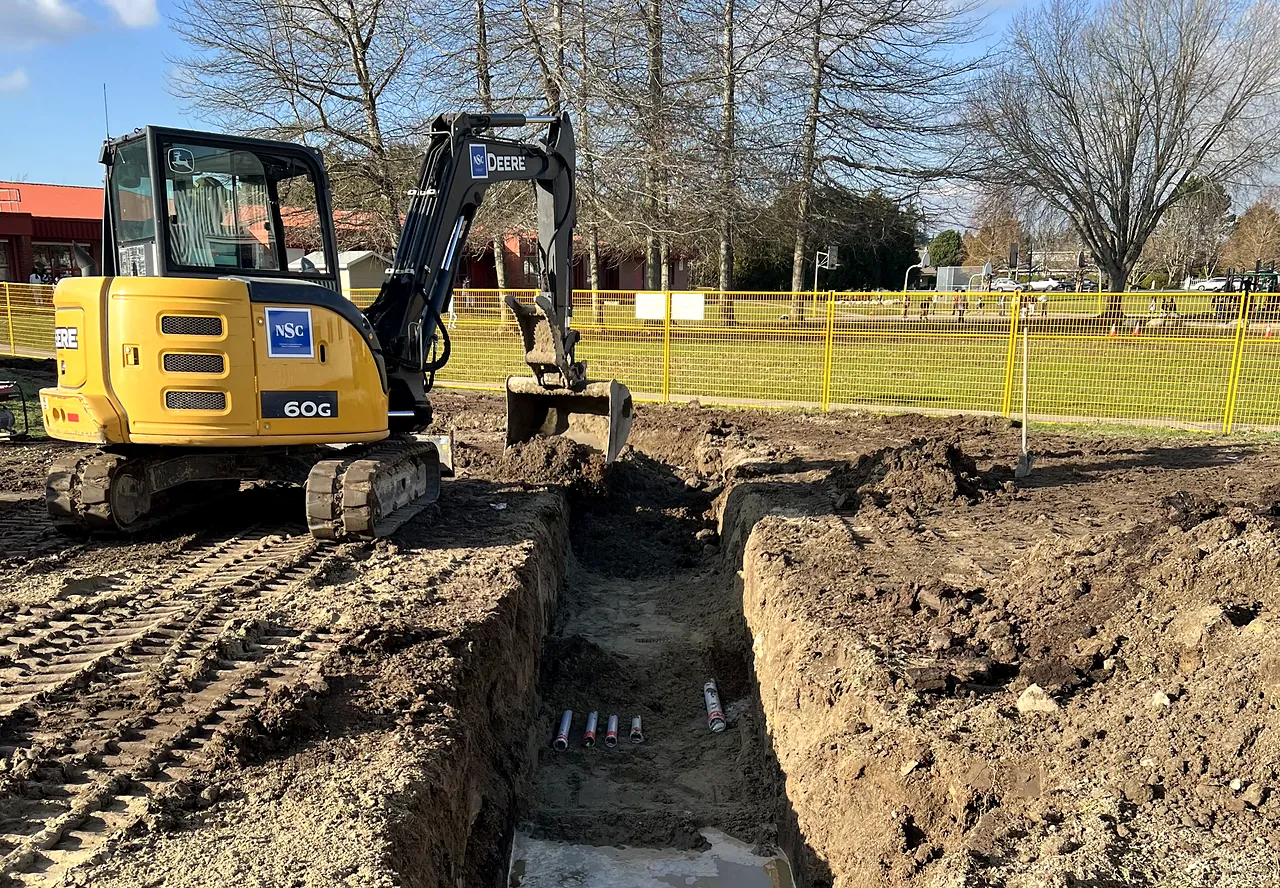Mini excavator opening a duct trench with precast box for the portables