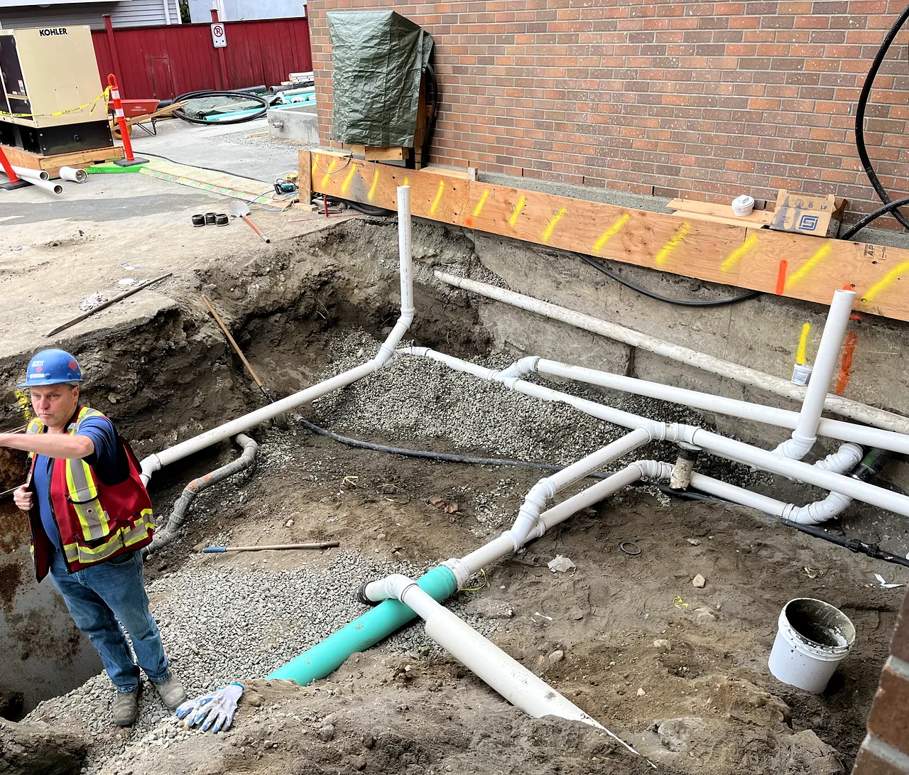 Storm and sanitary piping being installed beside the building