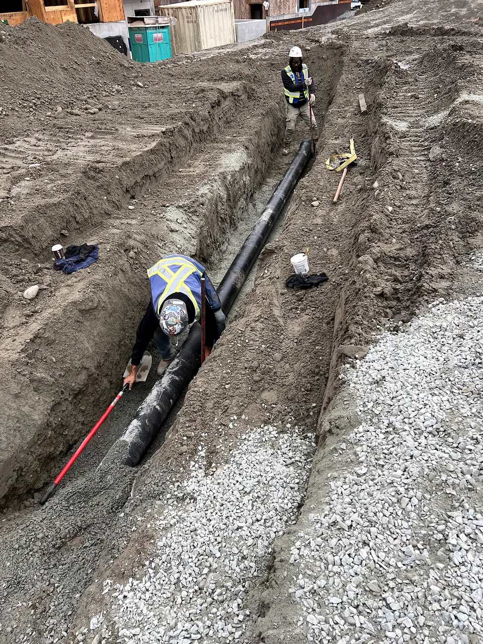 Crew laying pipe in a long trench
