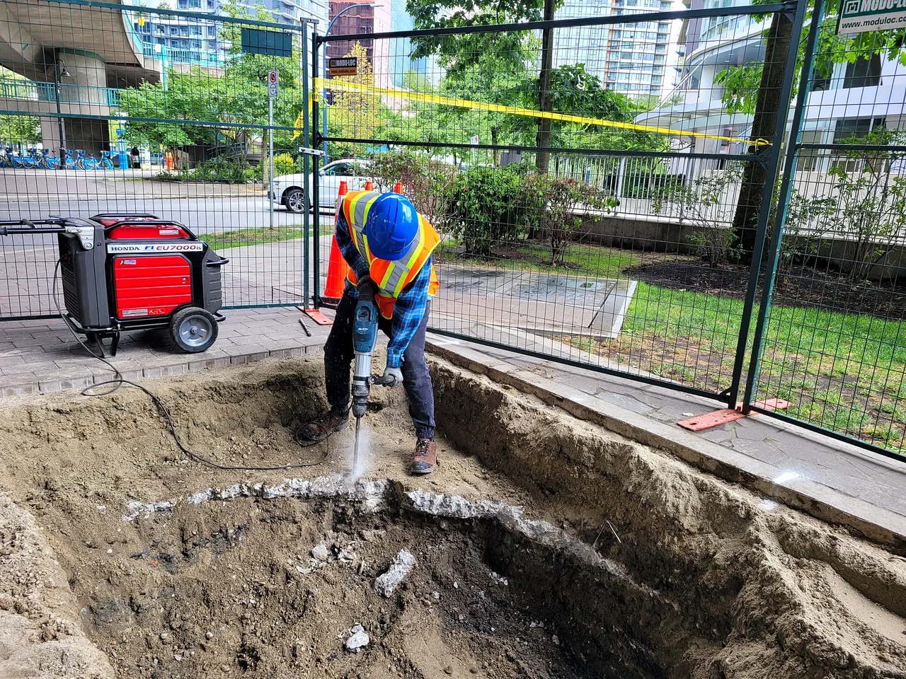 Worker breaking out concrete for a service trench at Coopers Park
