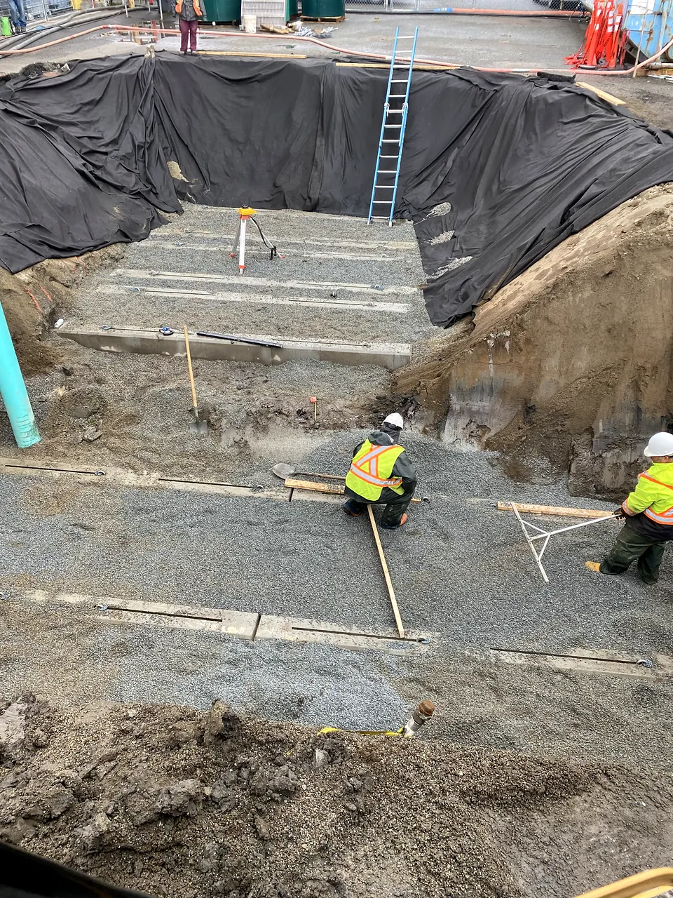 Crew grading bedding in the lined tank excavation