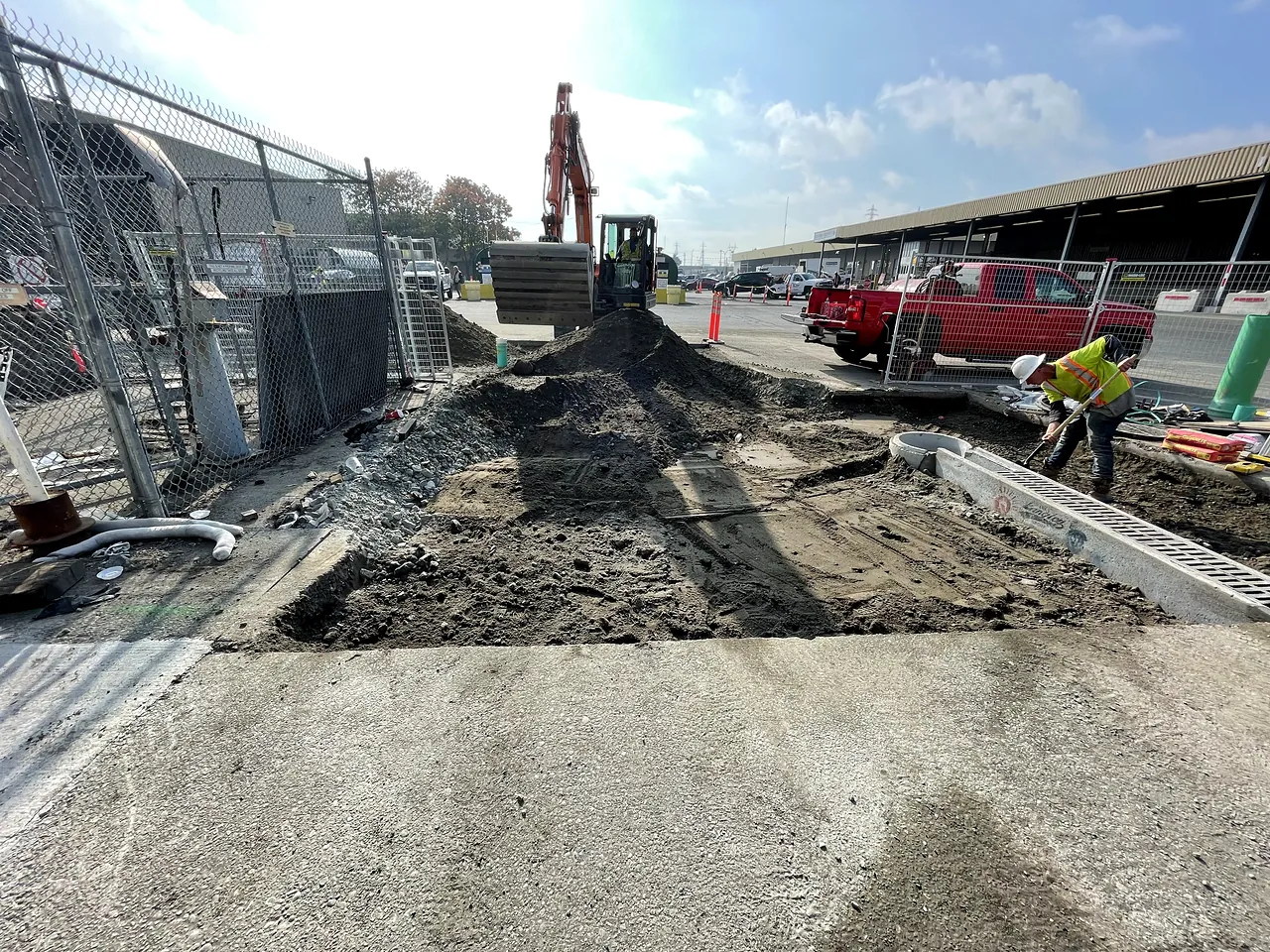 Excavator and worker finishing grade at the trench drain