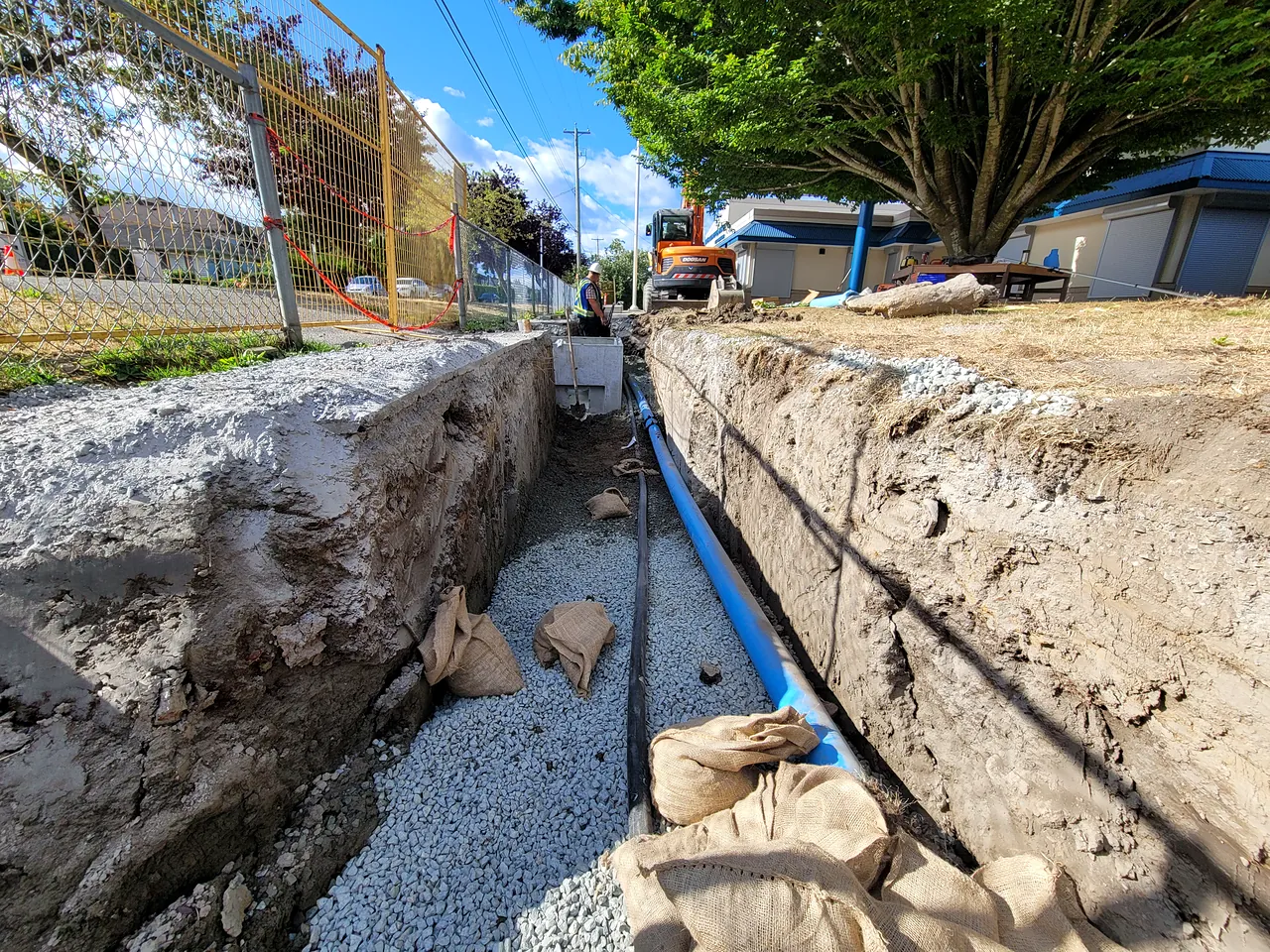 Water service trench with new PVC pipe and excavator at McKinney Elementary