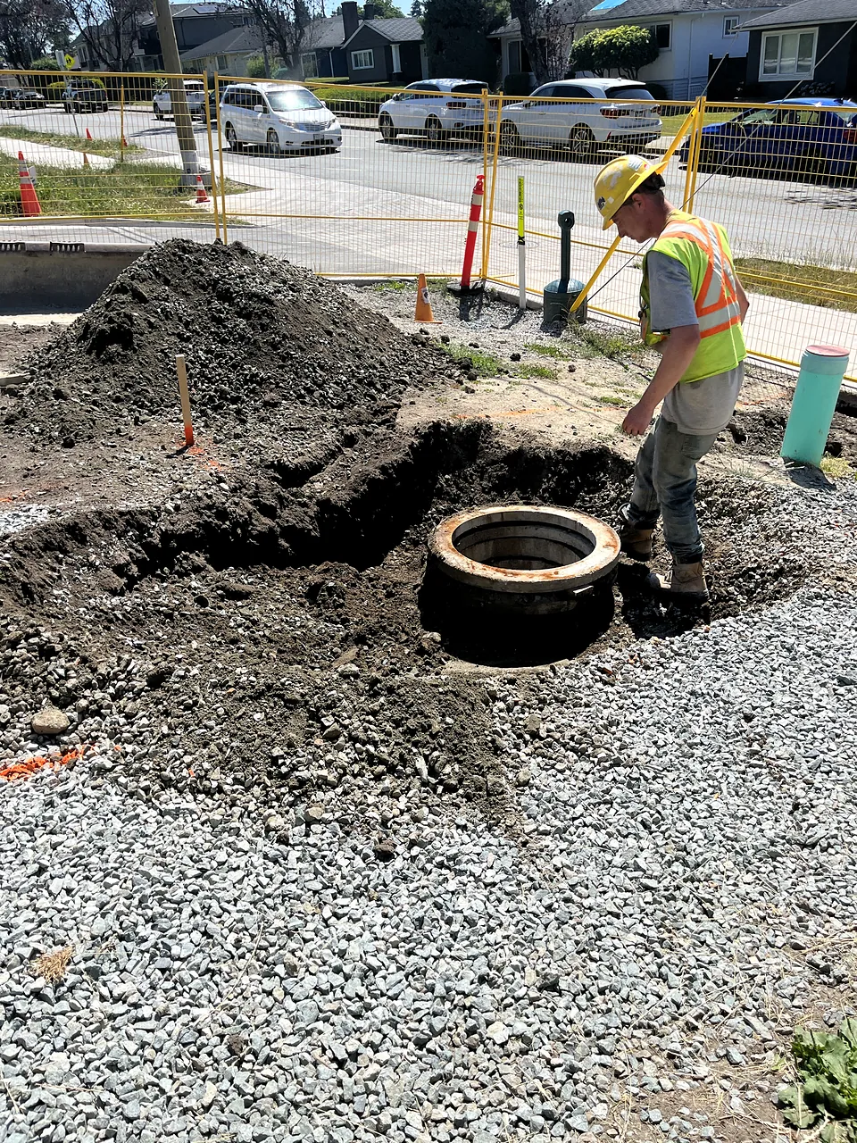 Worker setting a manhole section in the excavation