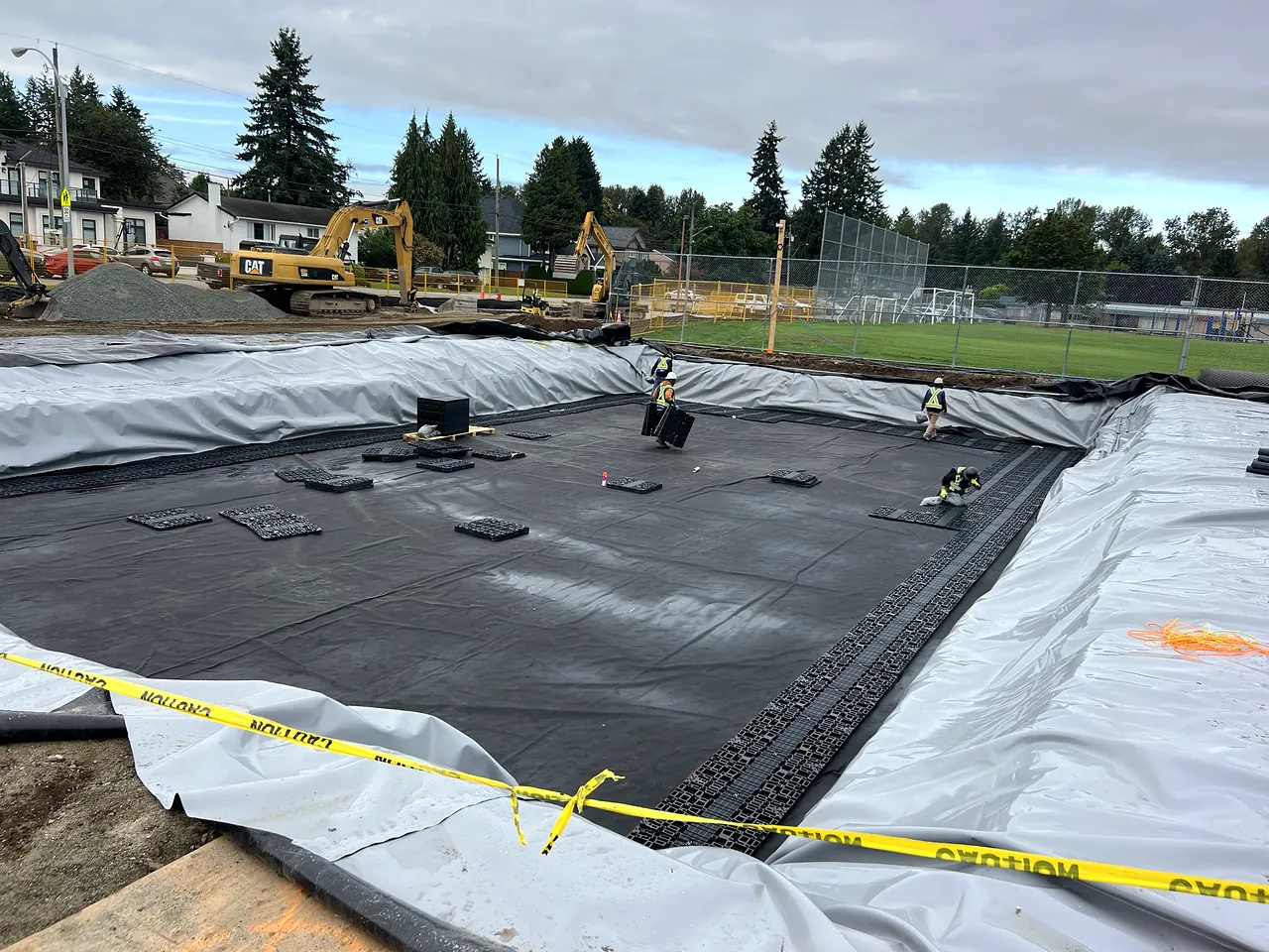 NSC crew placing detention tank modules with CAT excavators behind, Guildford Park