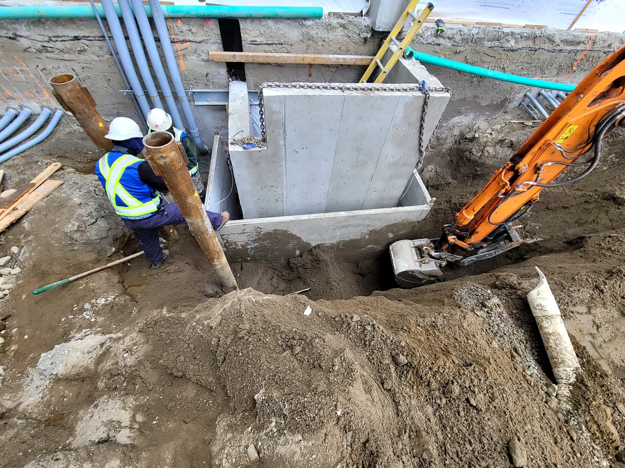 Crew setting a precast chamber with electrical ducts in the excavation